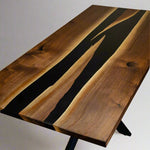 top down angle of a rectangular dining room table with two conjoining rivers of black epoxy in the middle.